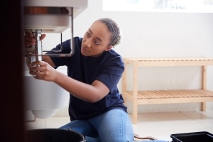 Plumber fixing leaking pipe in home to prevent potentially costly water damage