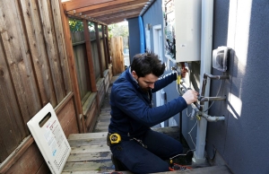 Dino from Caccia Plumbing works on a water heater.