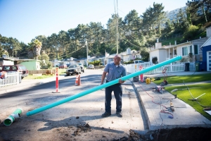 Caccia employee standing outside home with replacement portion of sewer pipe for trenchless repair