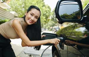 A happy woman plugs her electric vehicle into a home charger