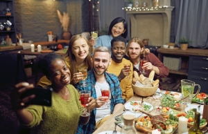 A group of Thanksgiving guests taking a selfie at a table with an elaborate dinner spread.