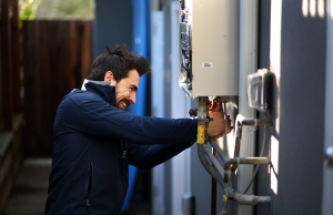 Dino from Caccia Plumbing working on a home plumbing repair outside of a home.