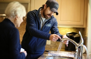 Dino from Caccia Plumbing inspecting the water pressure and flow from a kitchen sink faucet.