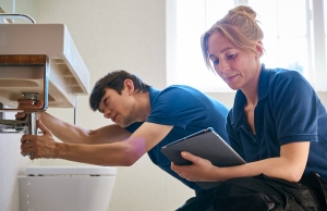 A woman and a man inspect a leaking sink.