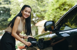 A woman plugs in her electric vehicle at home.