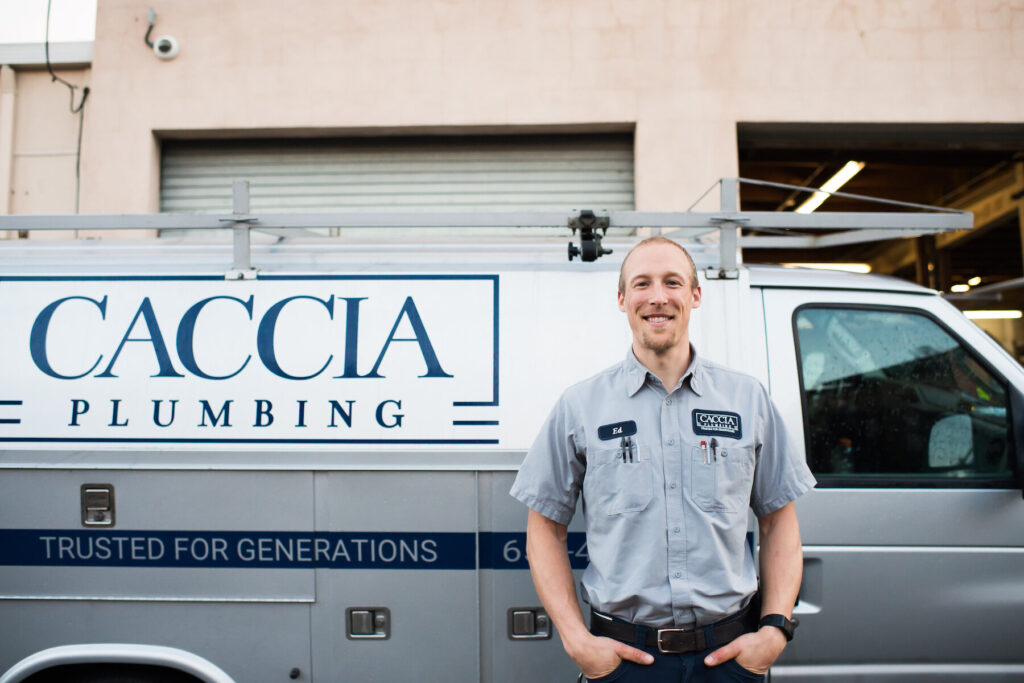 Caccia Plumbing plumber standing and smiling in front of a service truck.