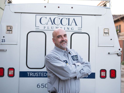 Caccia Plumbing plumber in front of a service truck