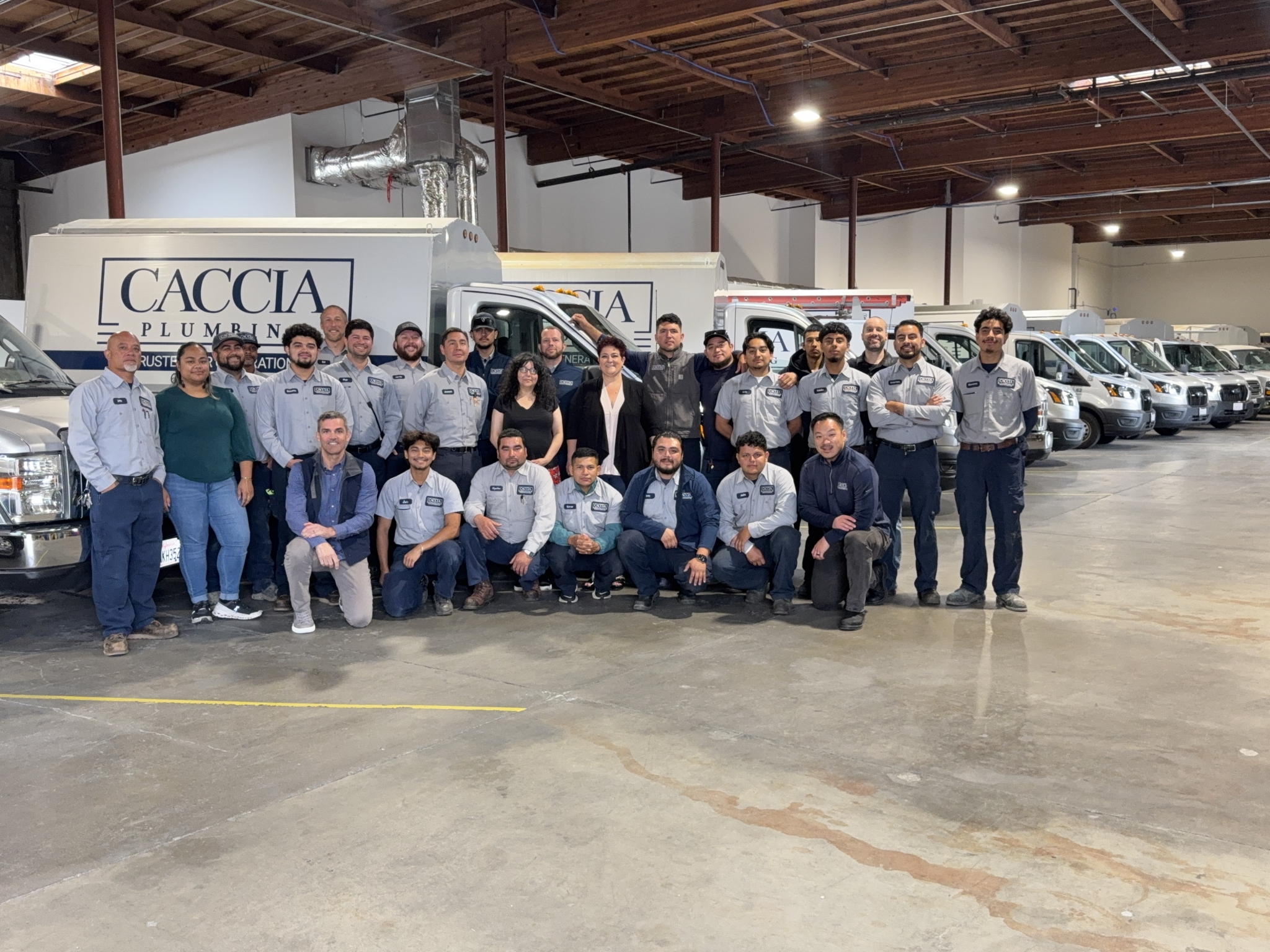 The team of Caccia plumbers, electricians, and support staff standing in front of a Caccia van