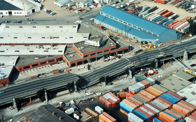 Aerial view of collapsed sections of the en:Cypress Viaduct of en:Interstate 880. [H.G. Wilshire, U.S. Geological Survey]
