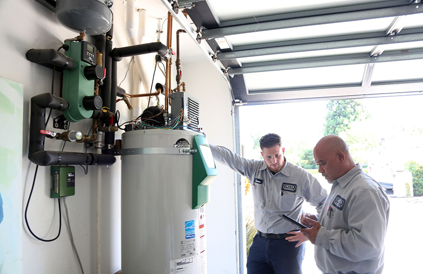 Ofa from Caccia Home services works on a customer's water heater with a colleague