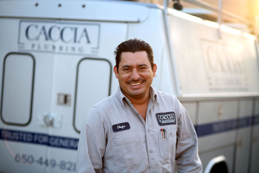 Hugo of Caccia Plumbing, smiling in front of service truck.