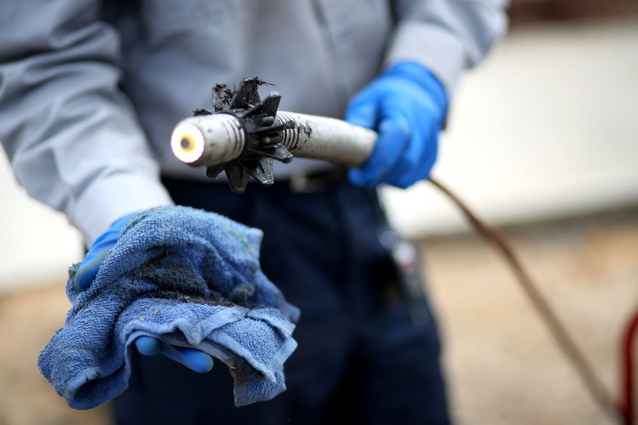 A plumber holds up the tip of a camera scope for sewer line inspection