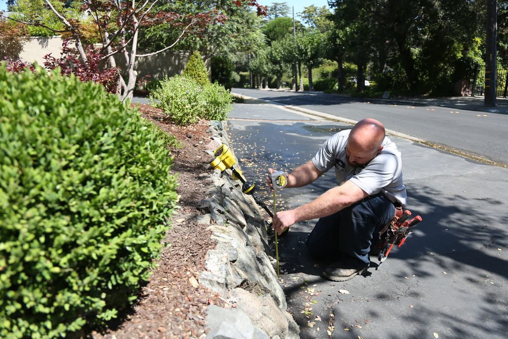 A plumber from Caccia Home Services uses a leak detection device to look for leaks underground