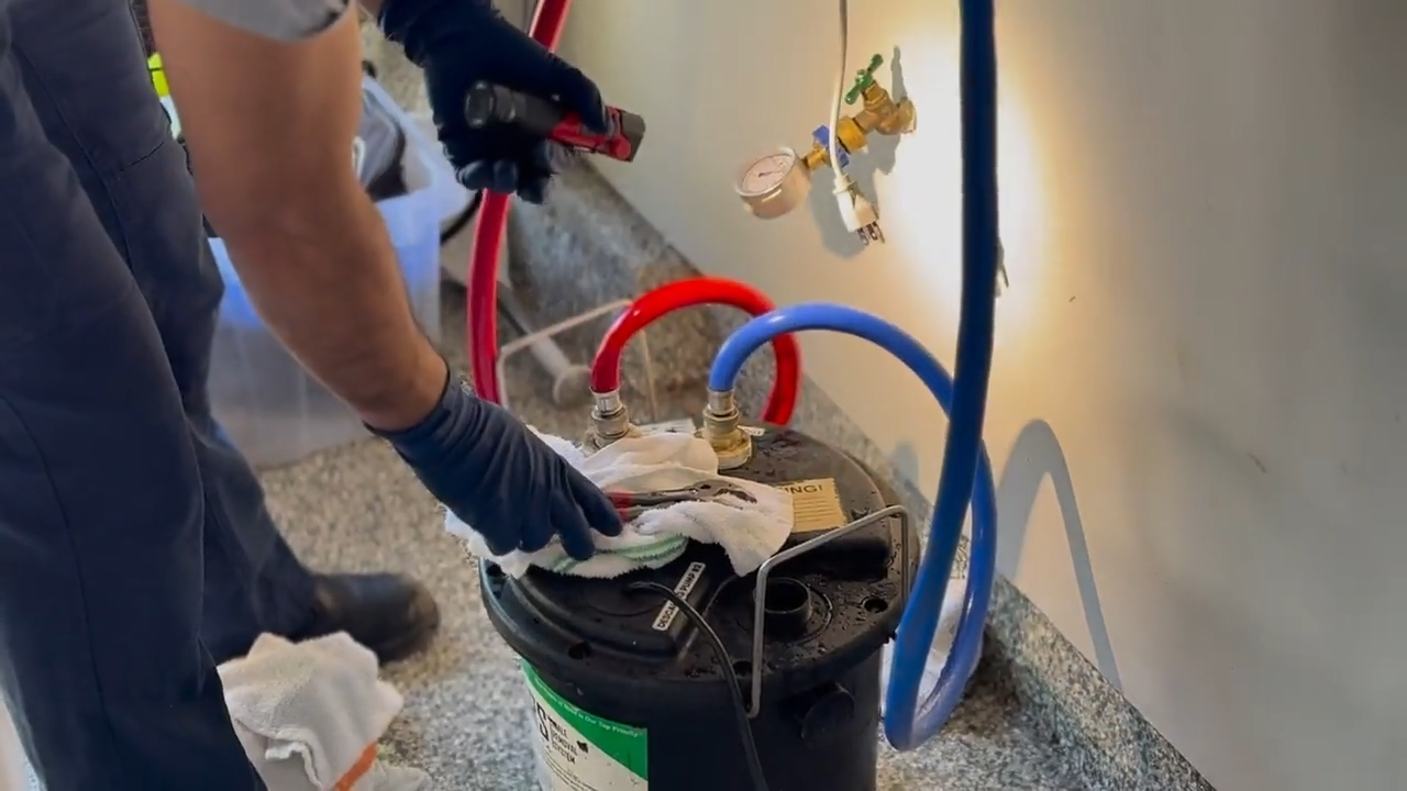 Cristian connects the red and blue pressure hose to the isolation service valves.