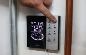 A technician from Caccia Home Services shows a customer how to set and schedule their water heater.
