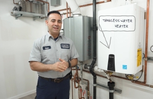 Geno standing next to a new tankless water heater in a customer's home.