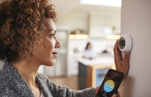 A woman adjusts the temperature at the thermostat